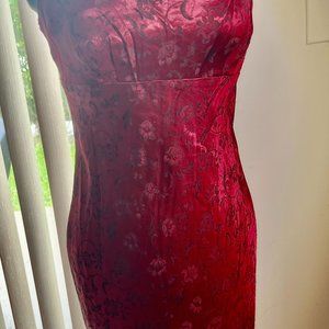 Red satin look long dress with red and black flowers and vines.